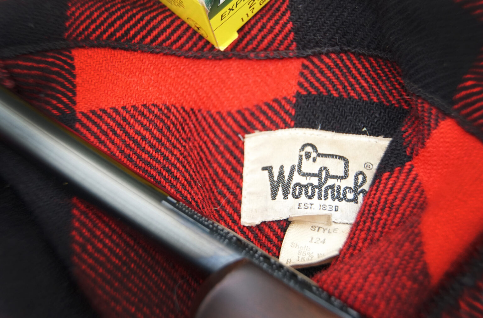 Closeup of a Woolrich tag in a red Buffalo-plaid jacket.
