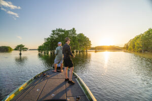 Two fishermen stand on the bow of a bass boat.