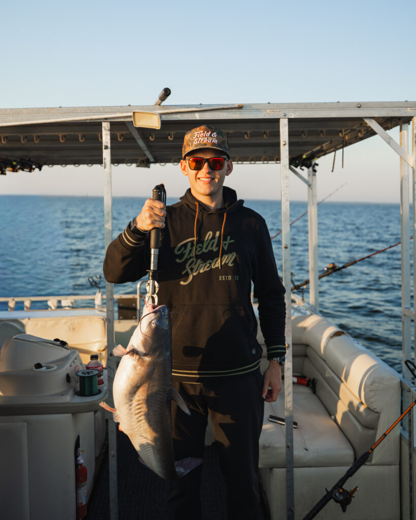 Corey Heim holds a catfish on a fishing boat