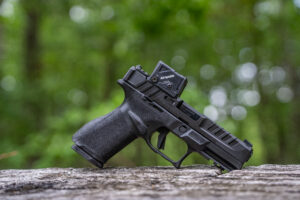 The new Springfield-Armory Echelon piston lying on a log in the woods.