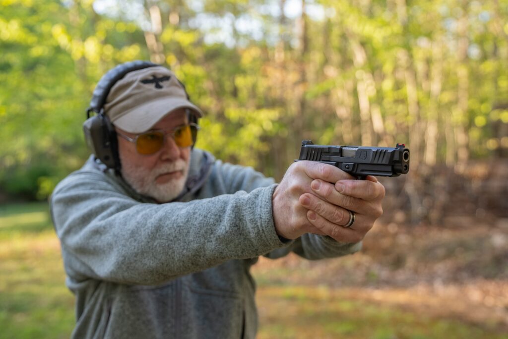 A man test fires the new Wilson Combat Bulwark pistol on an outdoor range.