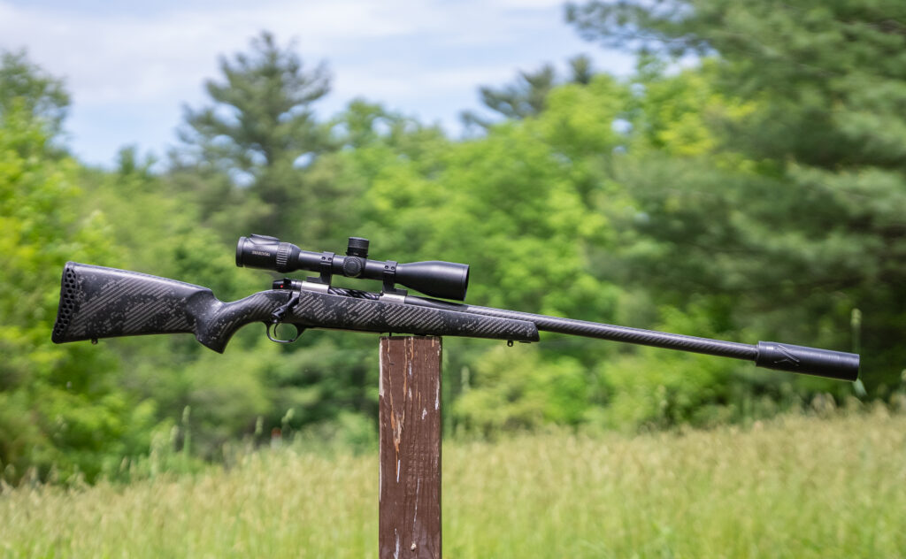 The Weatherby Mark V Backcountry Guide Ti rifle balanced on a post in a field.