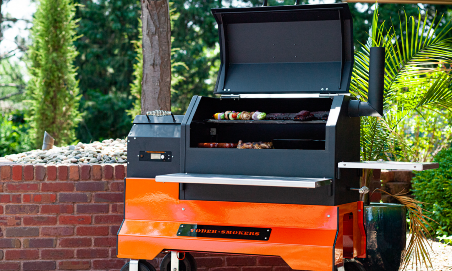 We Tested the Yoder Pellet Smoker—and Now We Get Why BBQ Pros Swear By It Yoder Smokers black and orange pellet grill with food cooking on grates outdoors