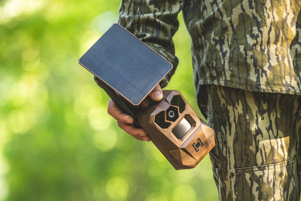 A hunter carries a Moultrie Edge 4 Solar camera in the field. 