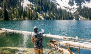 Angler fly fishing in alpine mountain lake