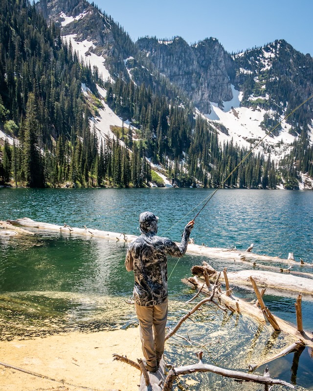Angler casting Greys Wing travel fly rod on alpine lake
