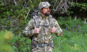 Hunter in woods wearing KUIU hoodie and pack