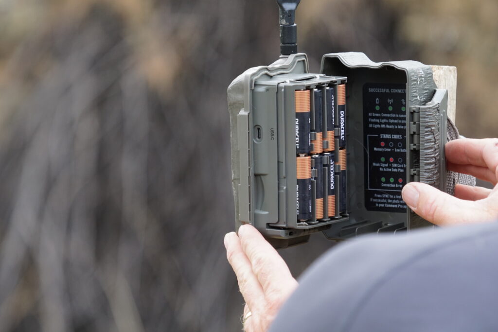 A person opens the door of a cell camera to check the batteries.