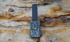 Browning Defender Pro Scout MAX HD DV cellular trail camera resting on a rock.
