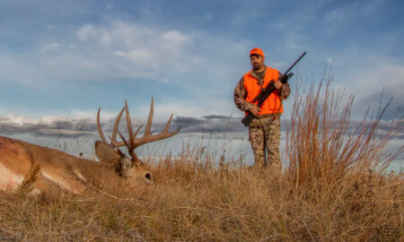 The Best Straight-Wall Deer Rifles for 2026 A hunter with a rifle approaches a whitetail buck he shot
