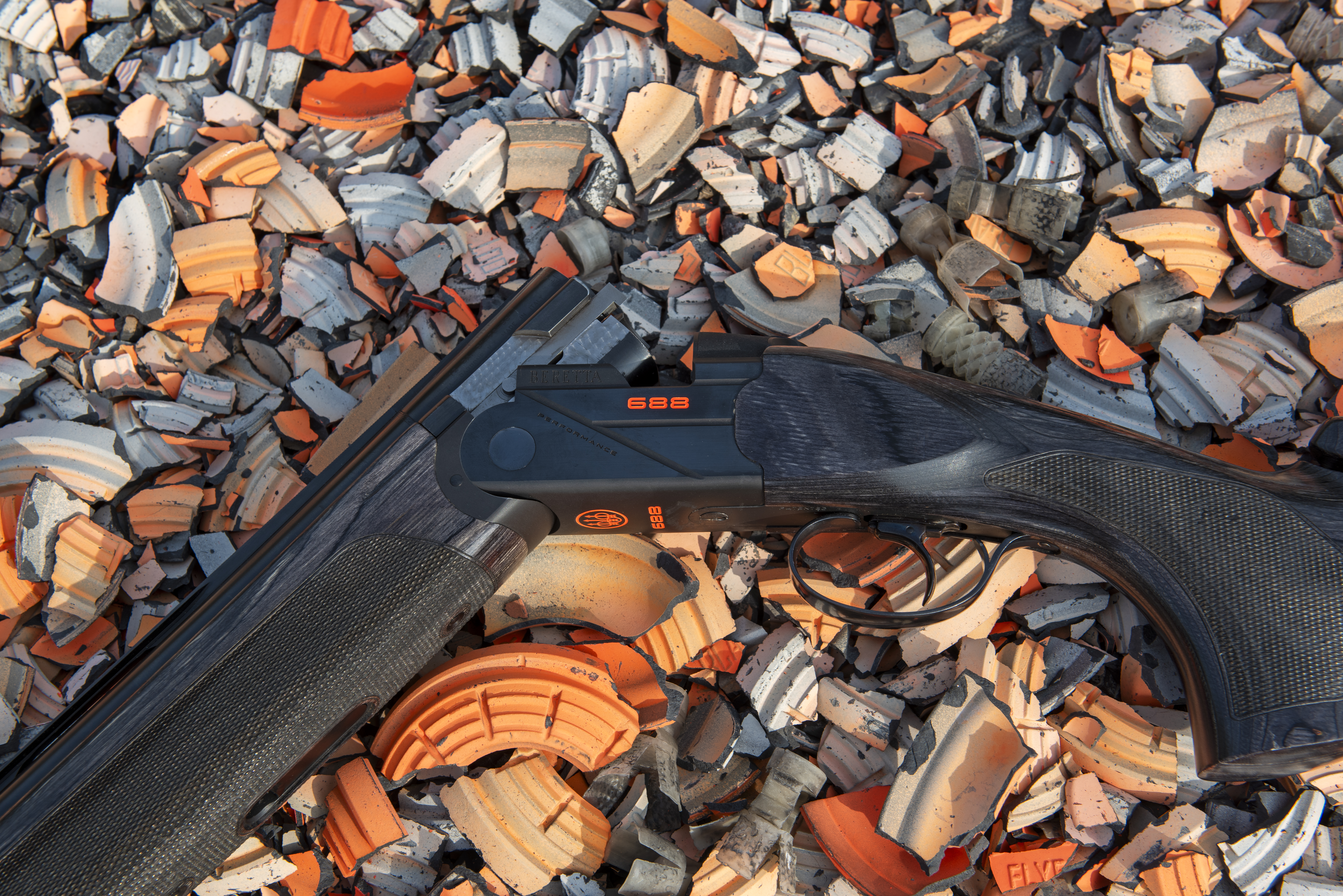 A closeup photo of the Beretta 688 action, resting on broken clay targets.