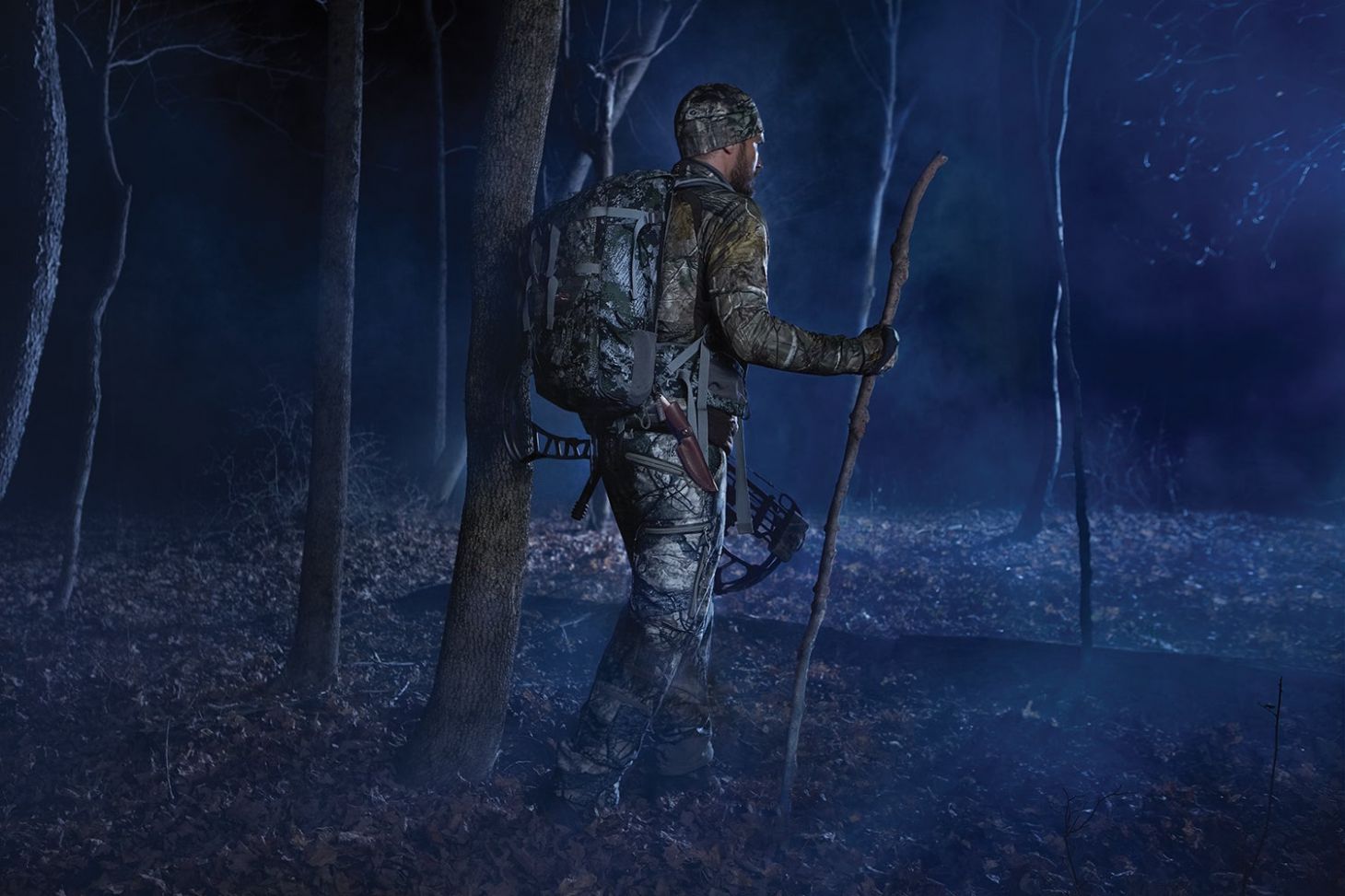camo-clad hunter hikes through woods in long before dawn