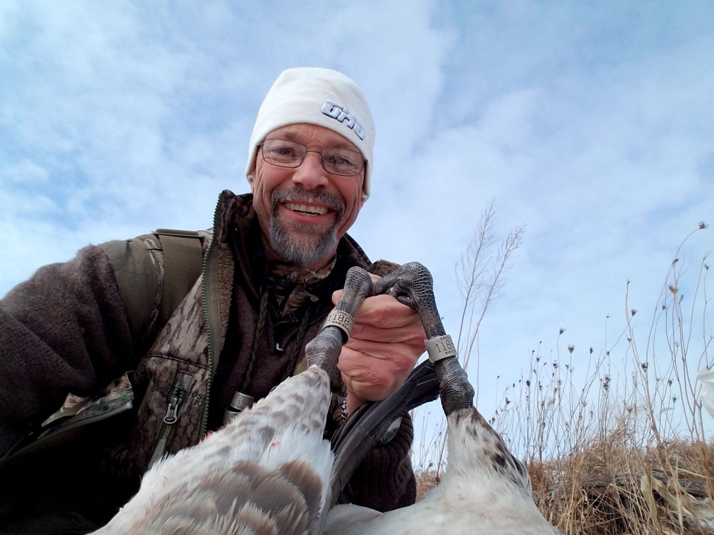 Man showing the legs of a dead goose.