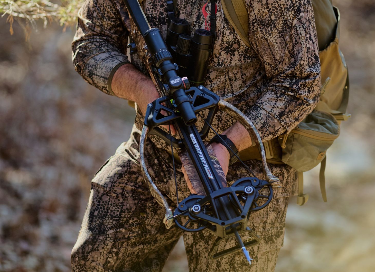 A hunter holds the new Excalibur Hybrid X crossbow while sneaking through the woods. 