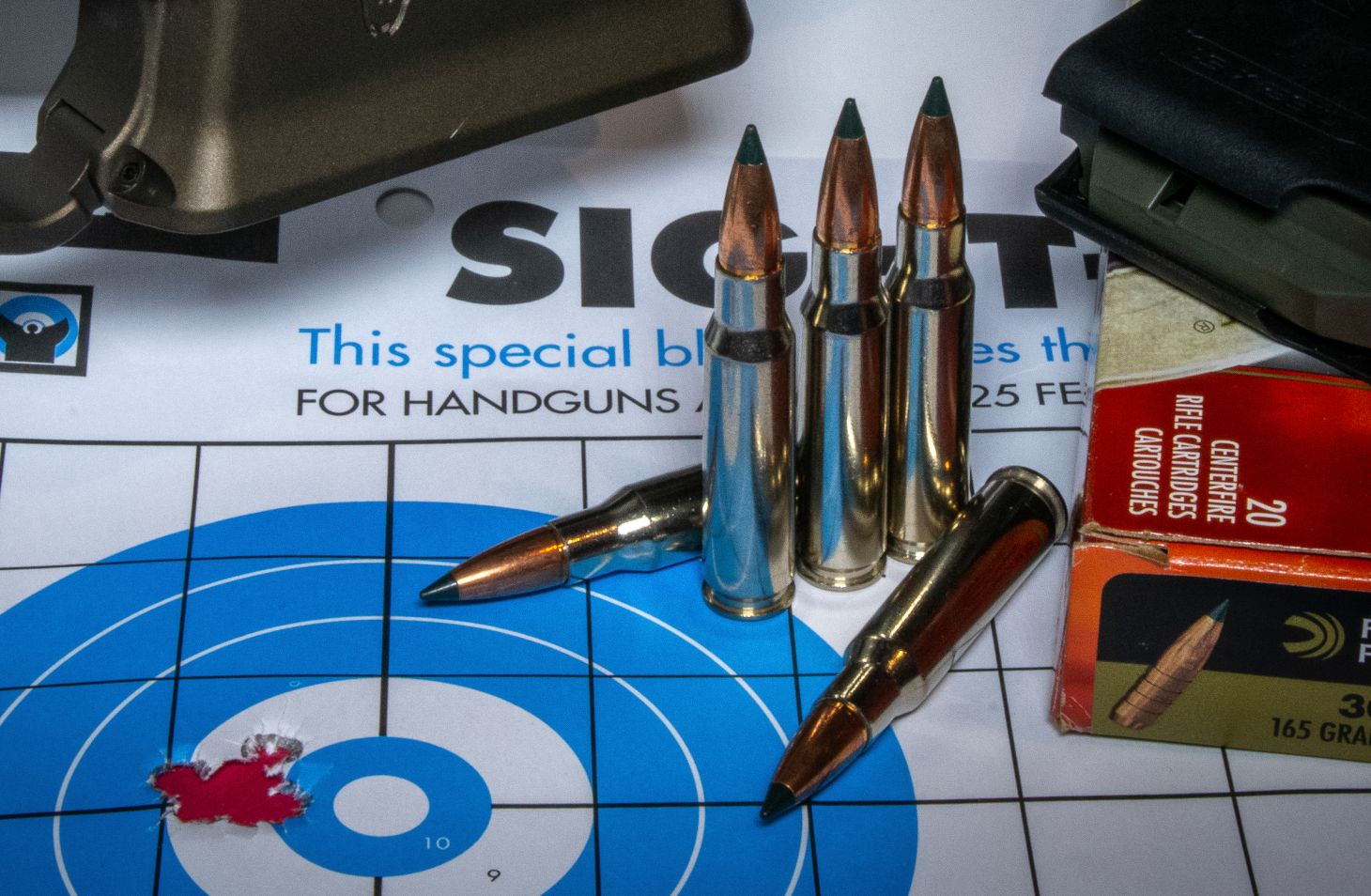 A rifle target with a small five-shot group and 308 ammo. 