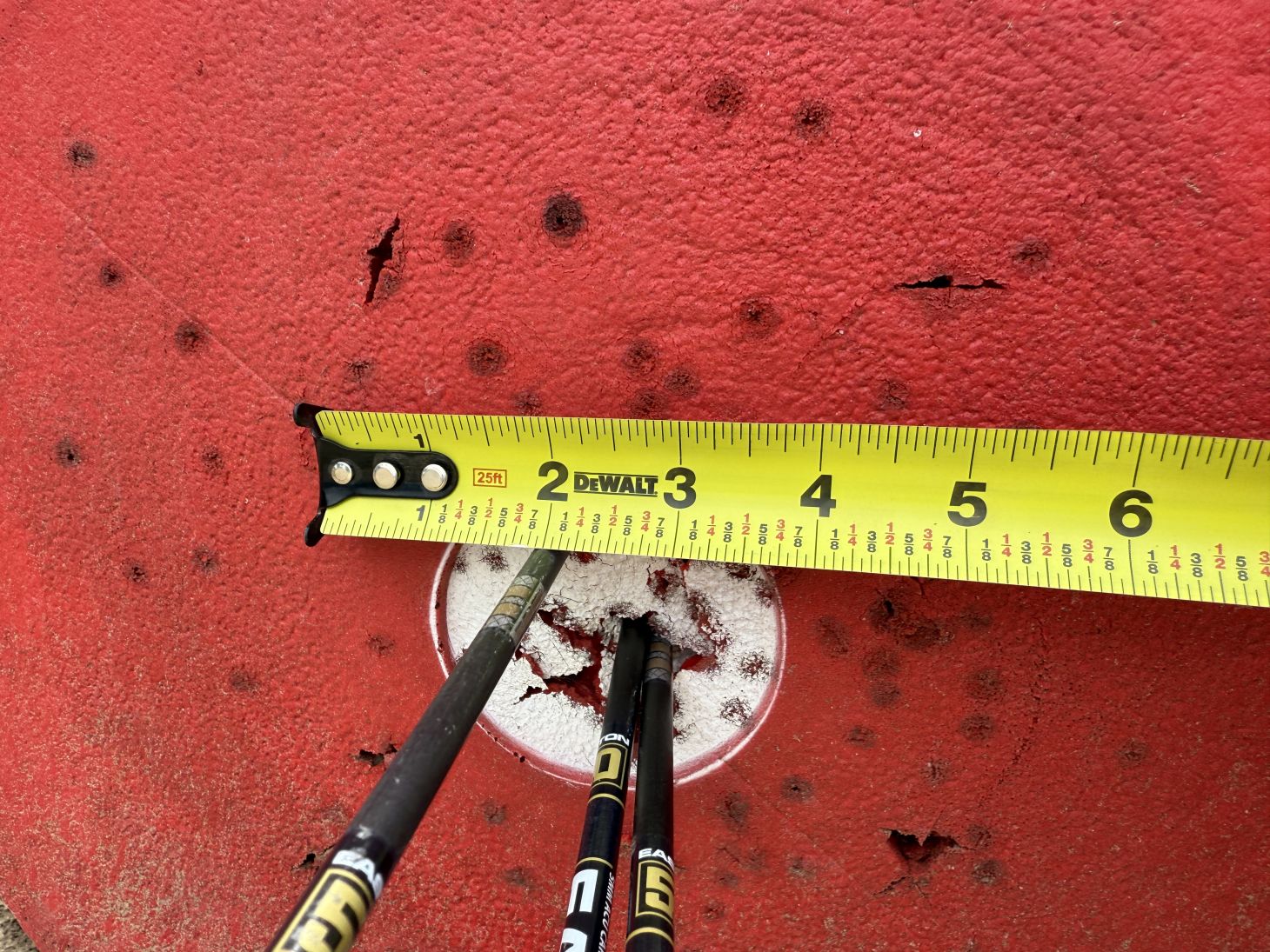 A group of arrows in a target with a tape measure showing the group measurement. 