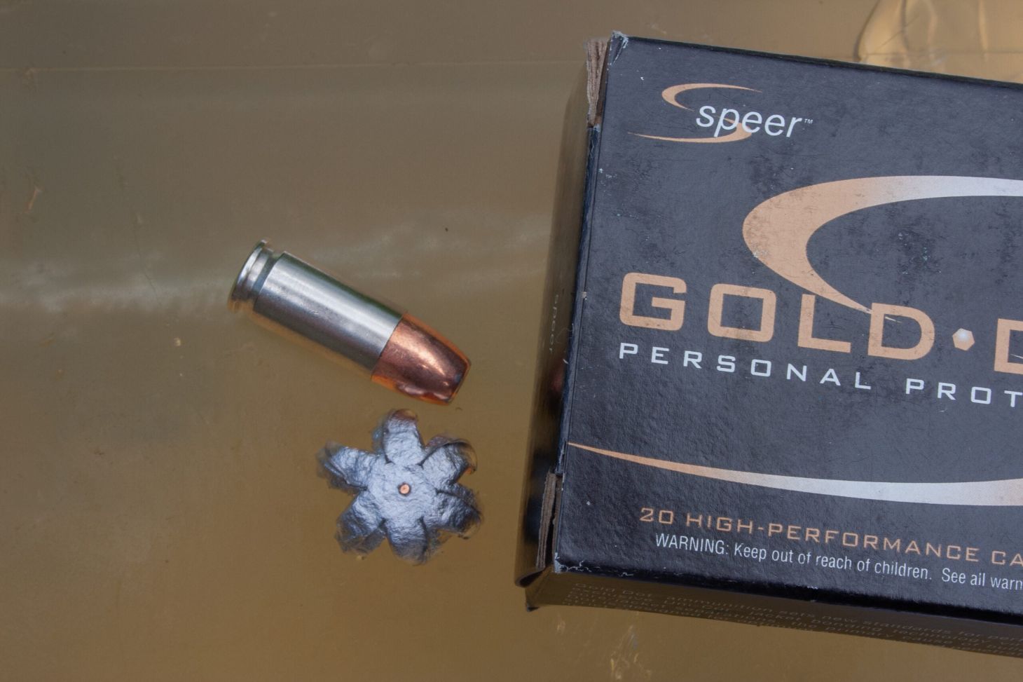 Box of 9mm ammo, fired bullet, and unfired cartridge sit atop a block of ballistics gel