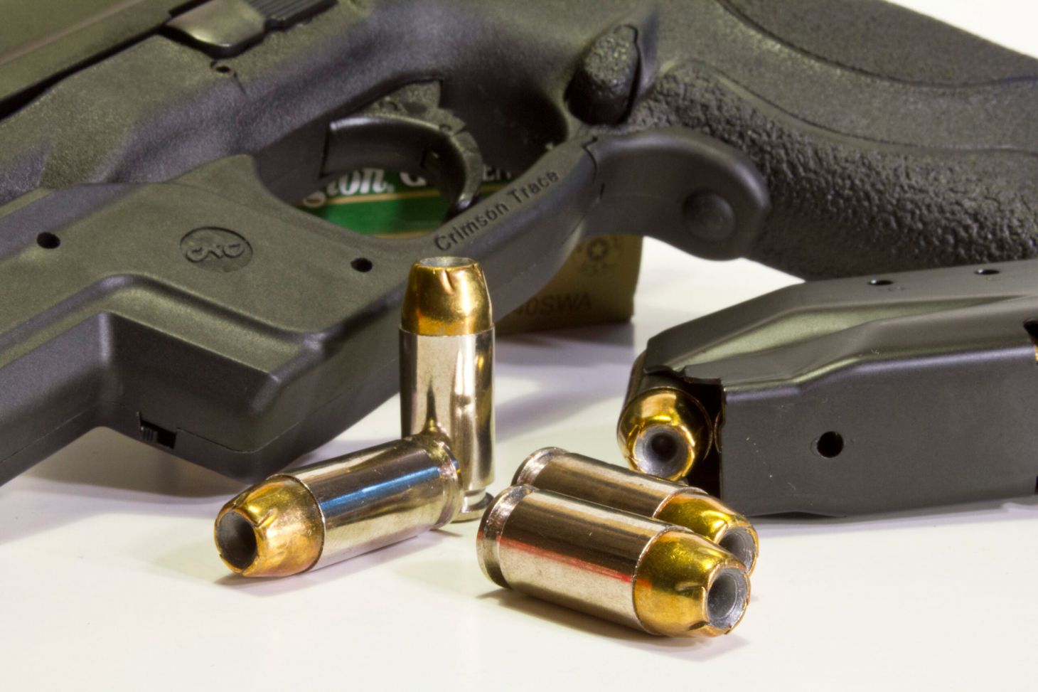 40 S&W cartridge lying near a pistol and magazine on white background