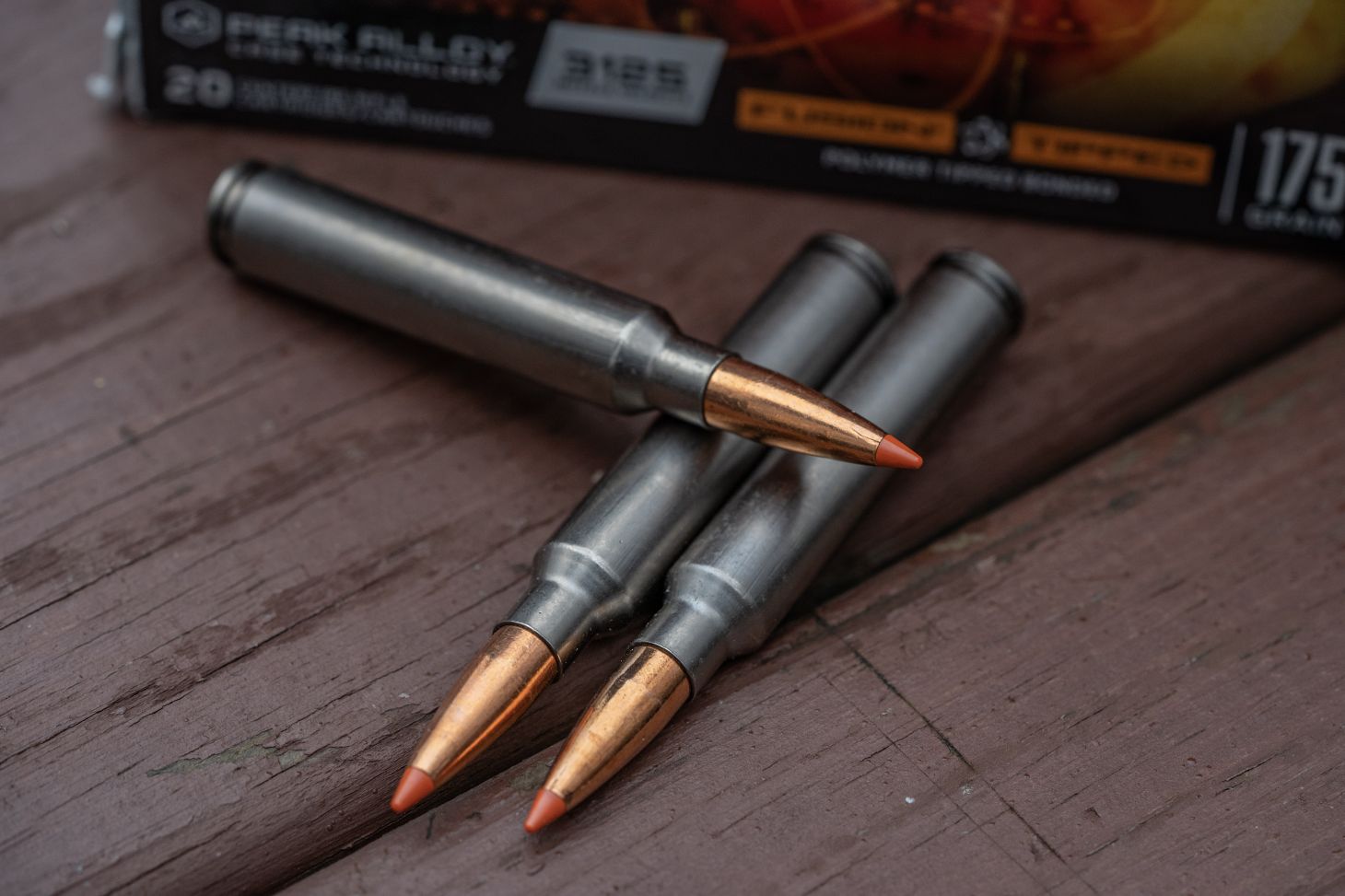 Three loose rifle cartridges sit near a box of Federal 7mm  Backcountry ammo.
