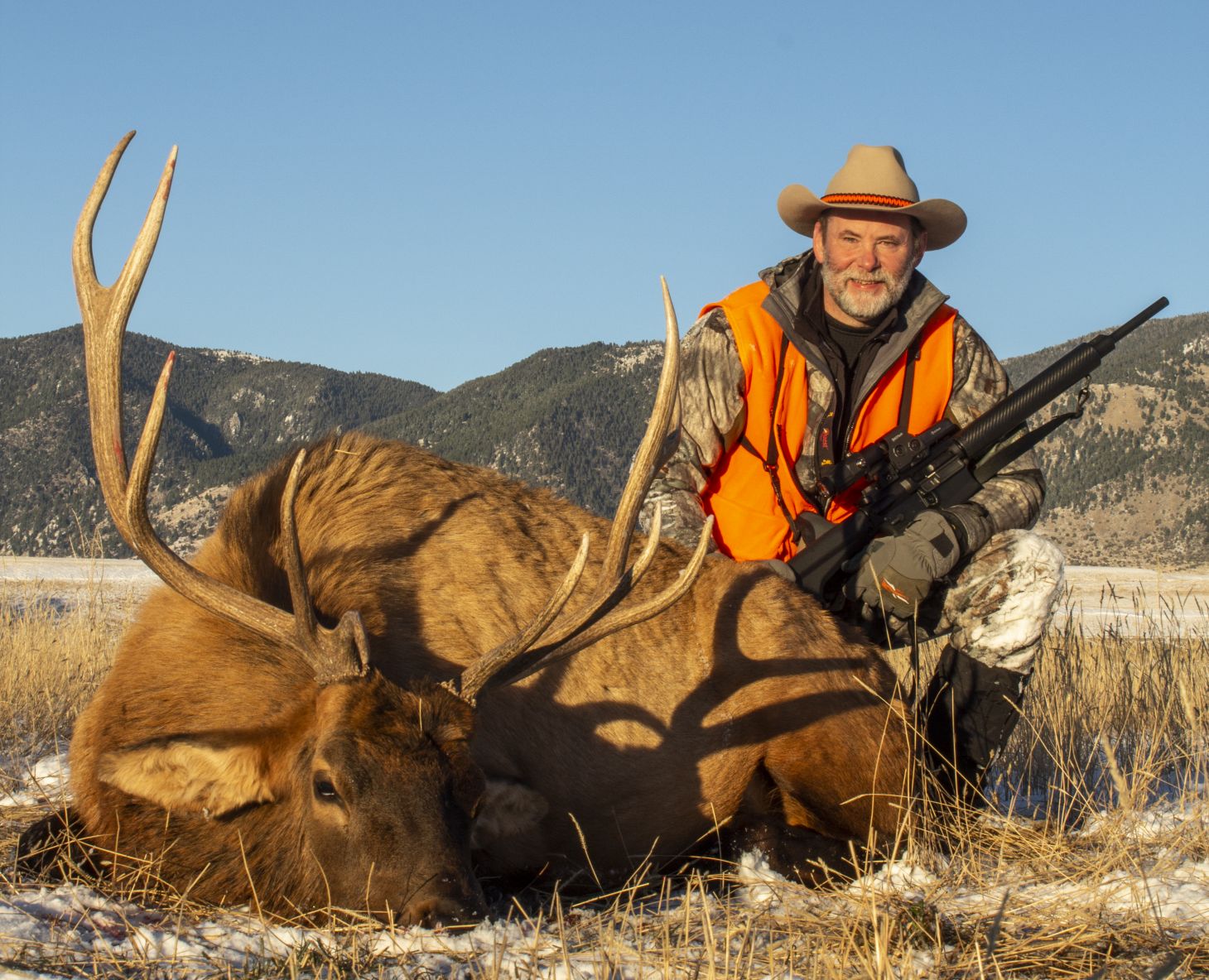 A hunter posing next to a bull elk he harvested.