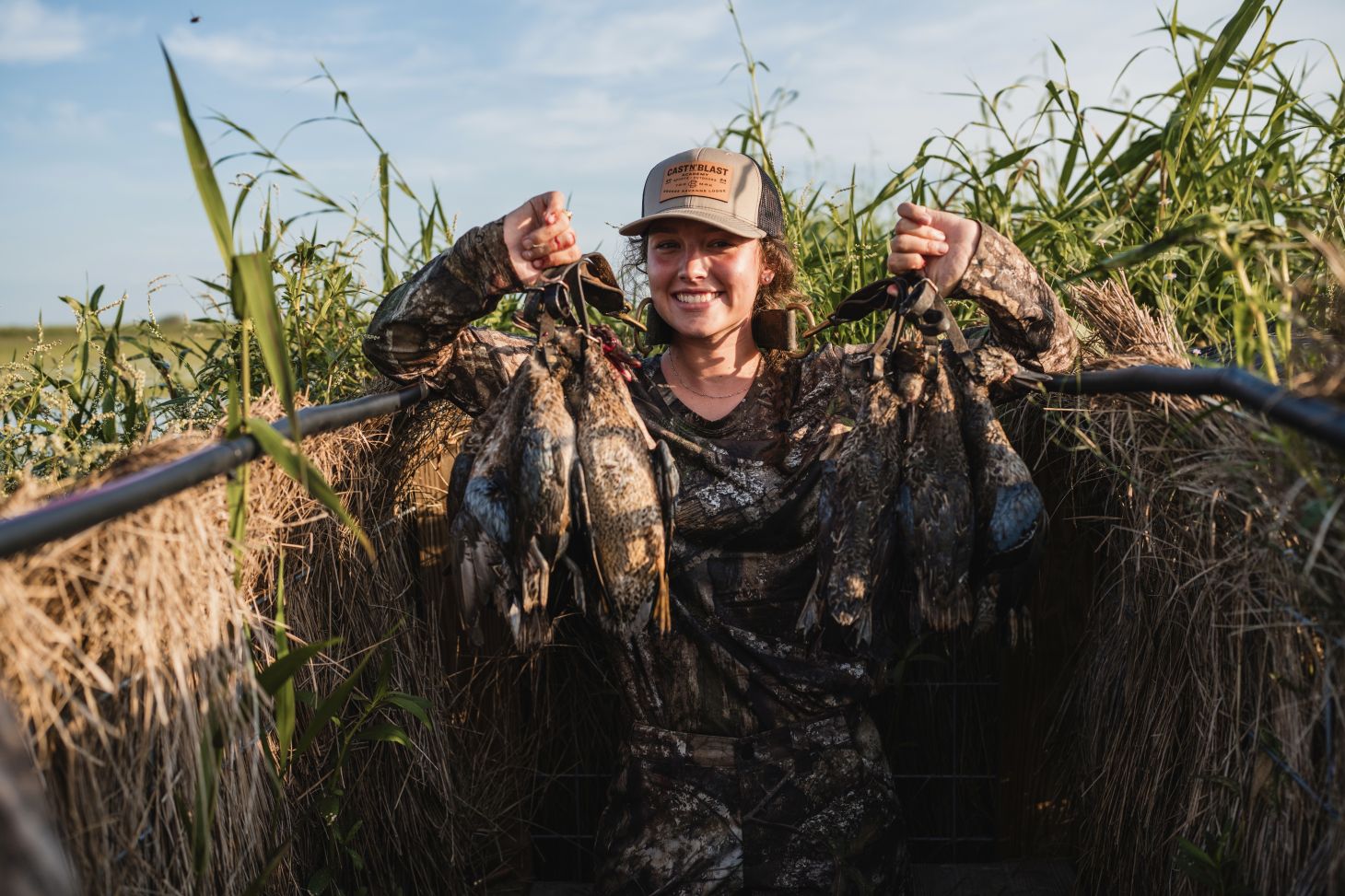 A female hunter in camouflage with dead teal ducks