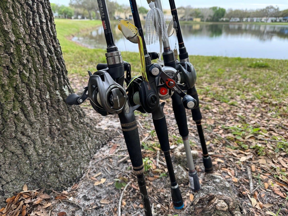 Baitcaster rod and reel combos lined up on grass during testing