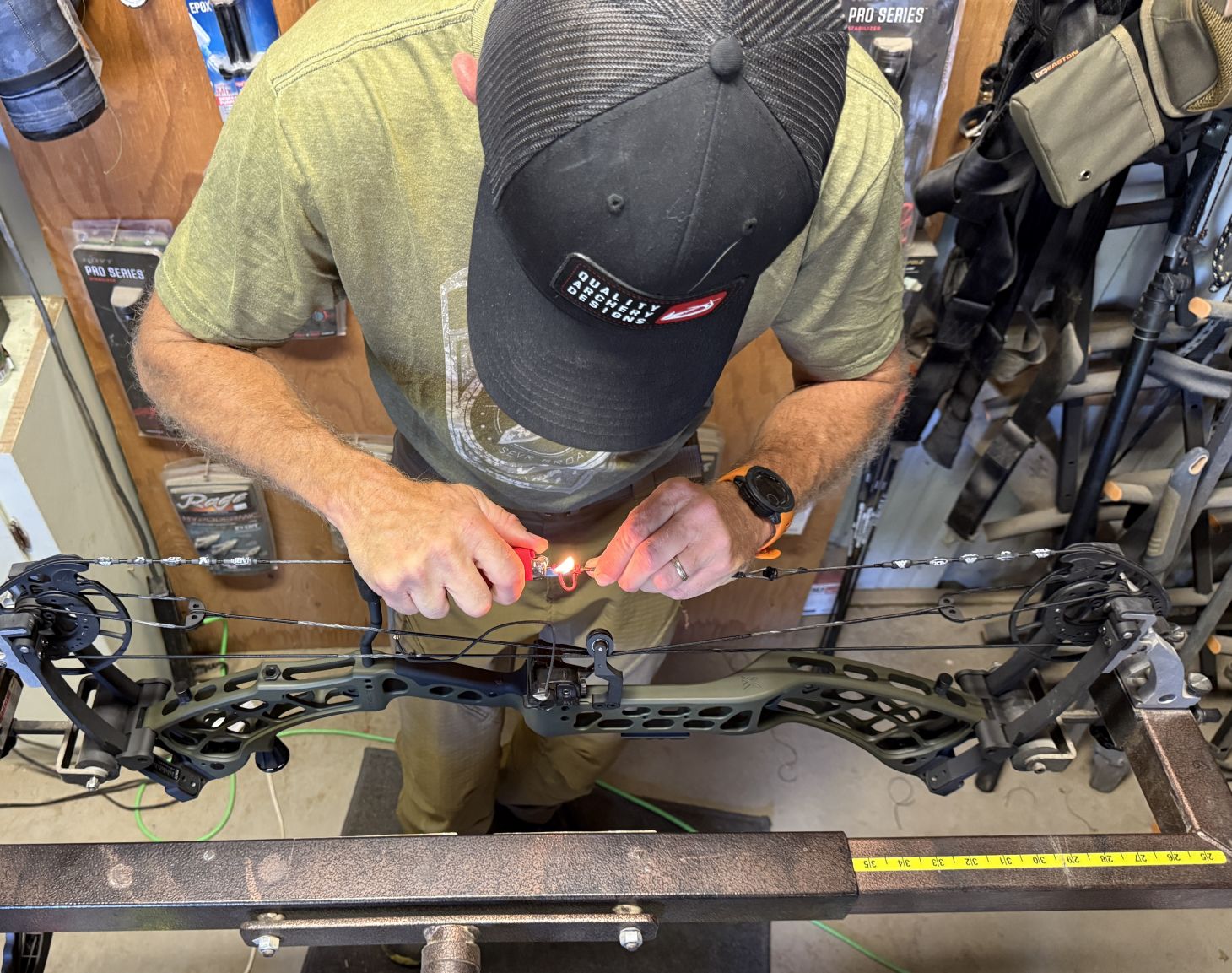 A person sets up a compound bow at a bench. 