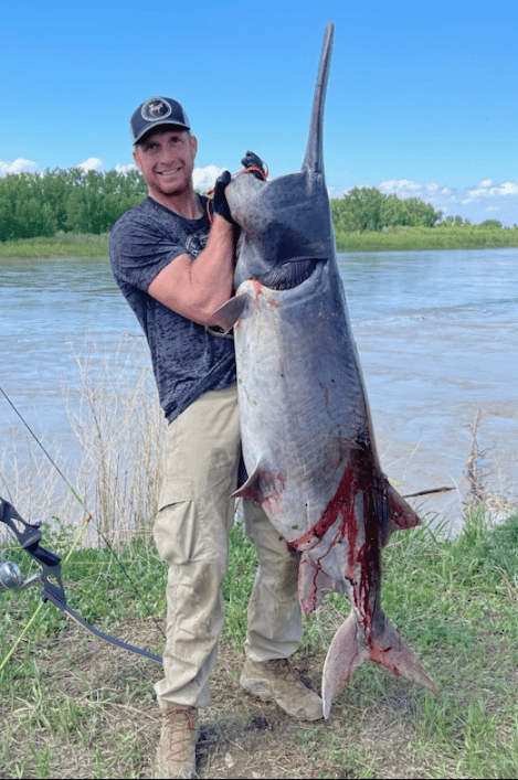 A bowfisherman poses with a world record paddlefish. 