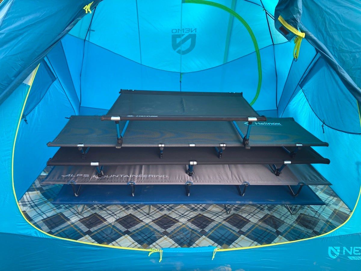 Four lightweight camping cots set up and stacked on top of each other in camping tent during testing