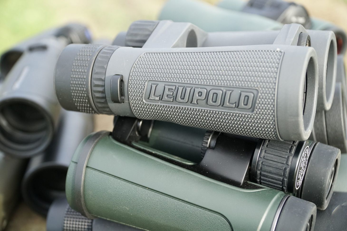 Leupold Santium 10x42 binocular sitting on a stack of other binoculars.