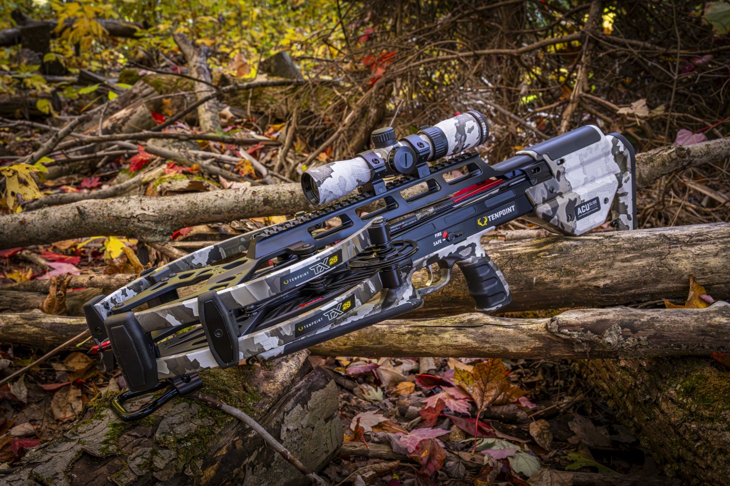 The new TenPoint TX-28 crossbow lying on logs in the woods. 