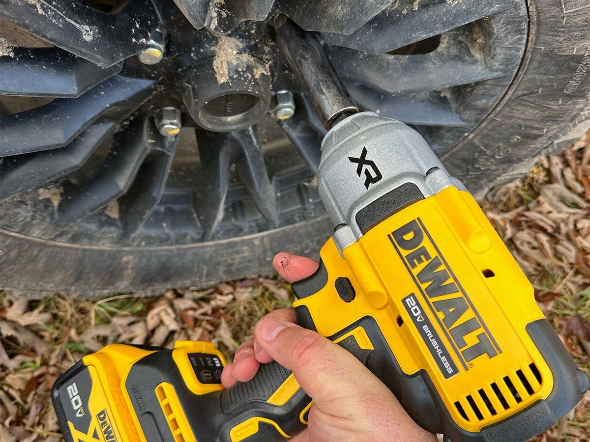 A DeWalt impact wrench loosening the lug nut of a Honda UTV tire