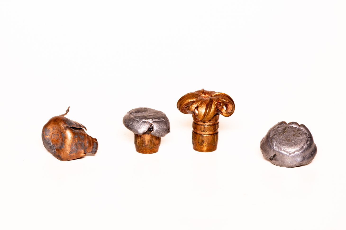 An array of fired bullets from elk cartridges on a white background. 