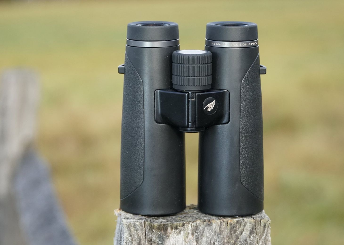 GPO Passion HD 10x42 binocular sitting on a fence post with field in background