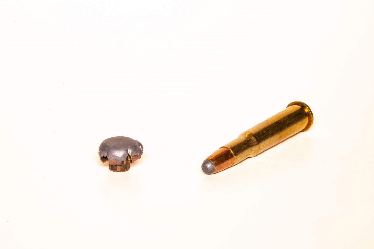 A 30-30 cartridge with a fired bullet on a white background. 
