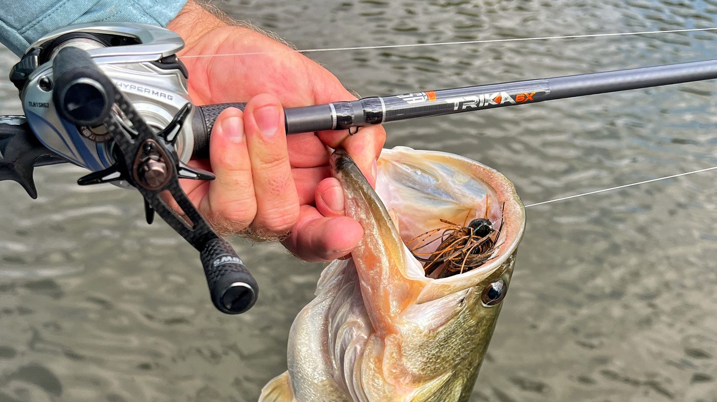 Anger's hand holding bass and fishing rod
