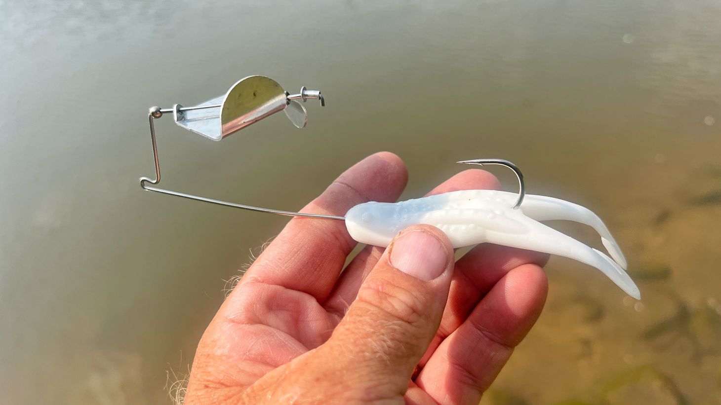Hand holding buzzbait and soft plastic toad