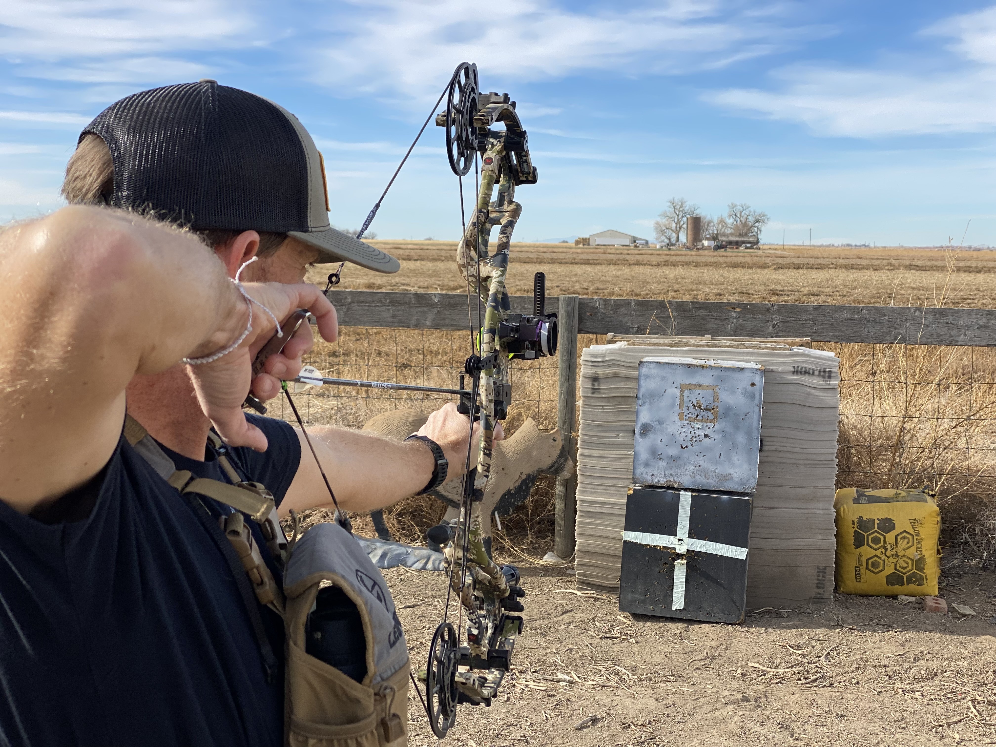 An archery shoots a bow into a target set up for walk-back tuning.