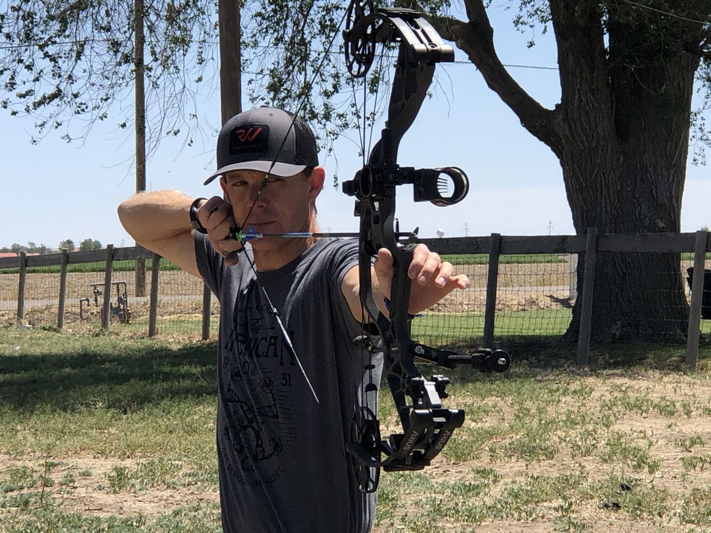 An archer shoots a bow into a target in a backyard.