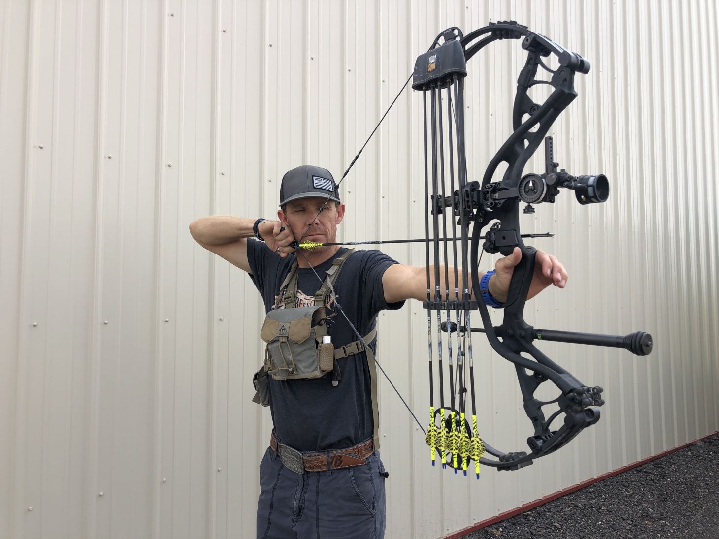 An archer shoots a compound bow in his yard. 