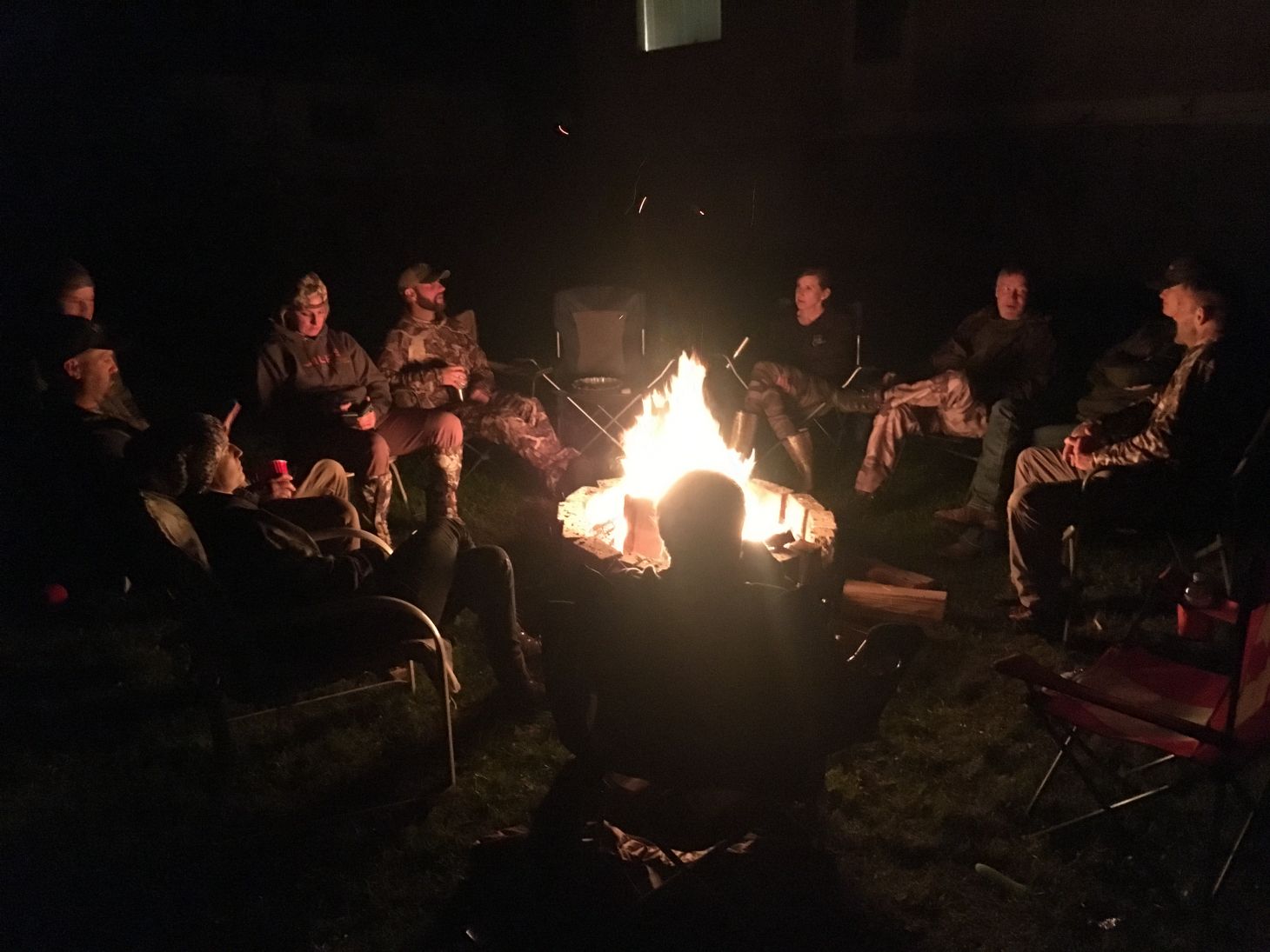 A group of people sit around a campfire.