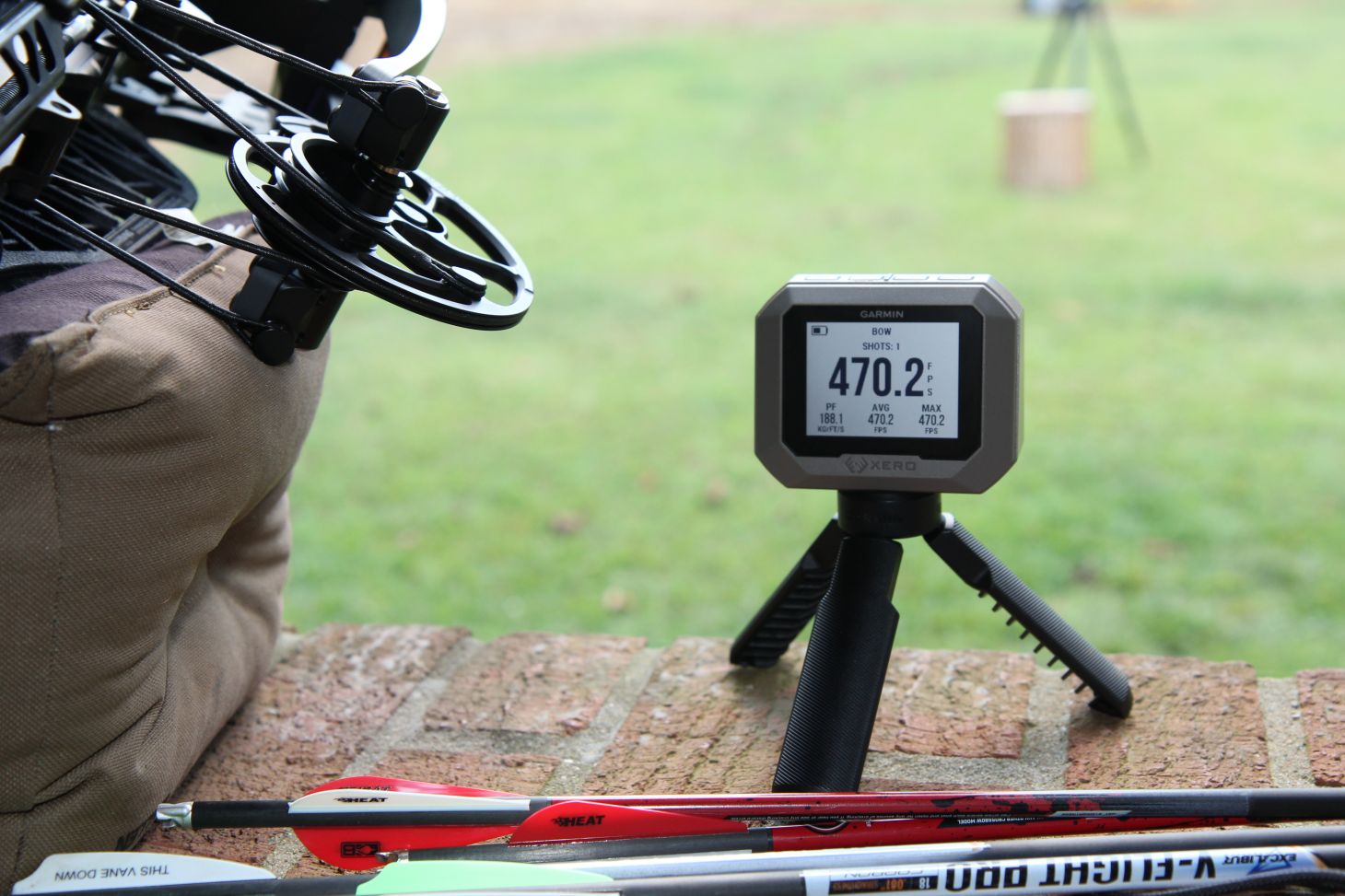 A digital chronograph on an archery range showing an arrow speed of 470.3 fps.