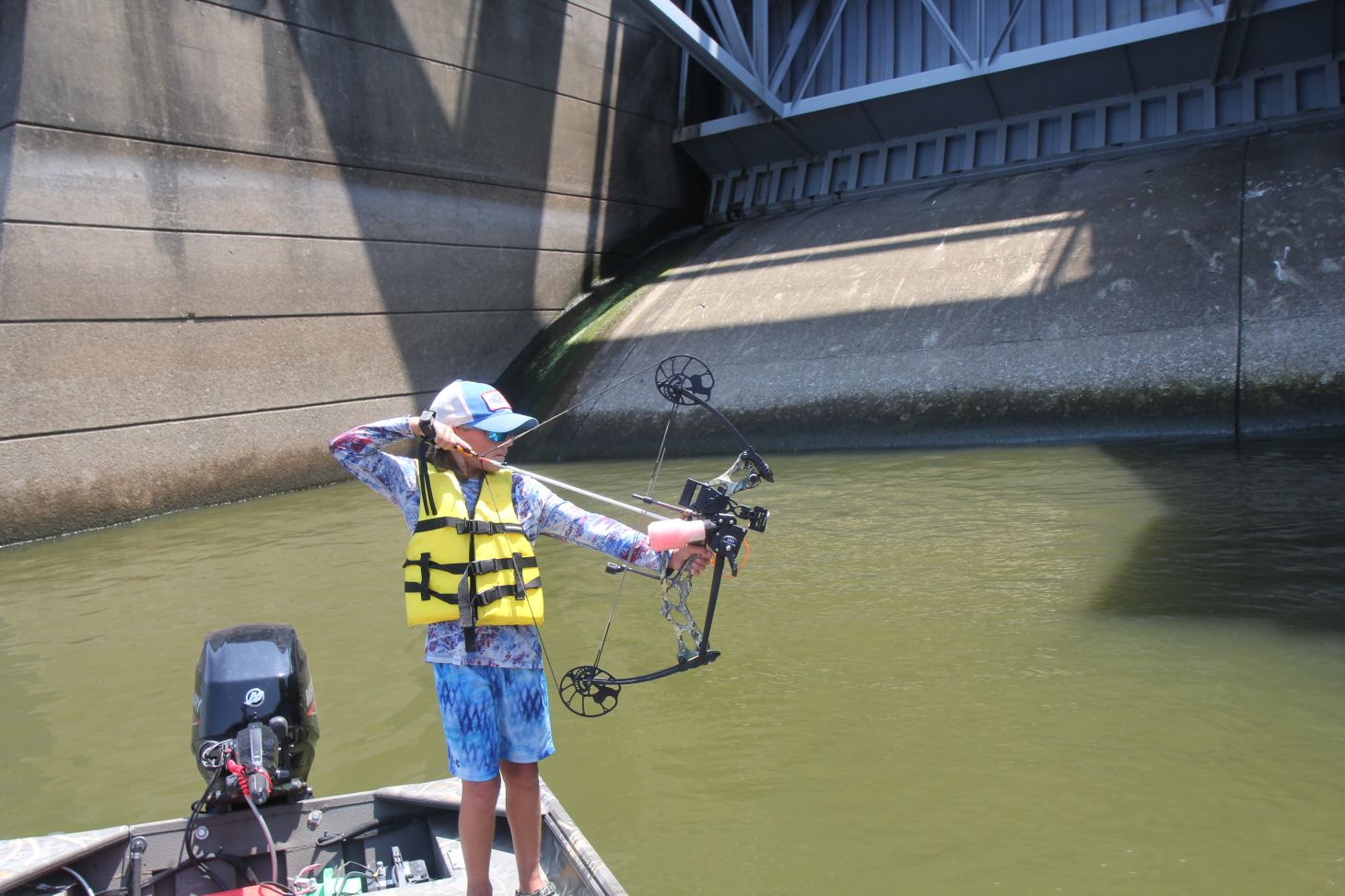 Bowfisherman at full draw on boat
