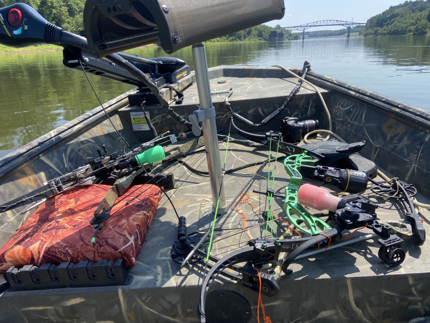 Multiple bows with bowfishing reels sit on the deck of a boat