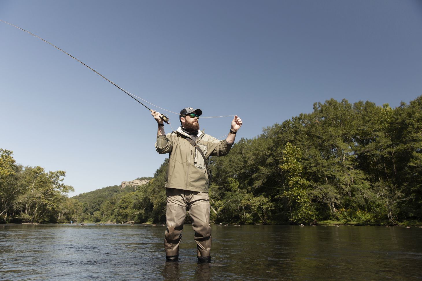 A fly angler casts for trout on a river