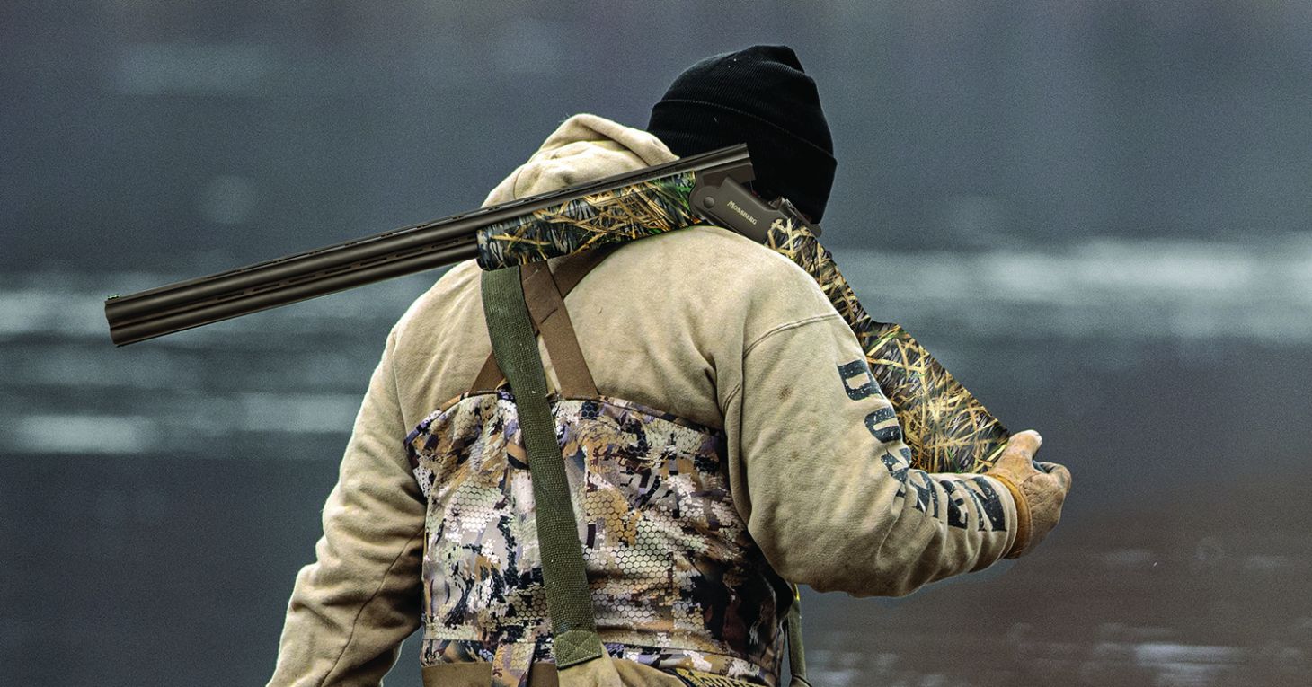 Waterfowl hunter walks with a Mossberg Silver Reserve Eventide shotgun over his shoulder.