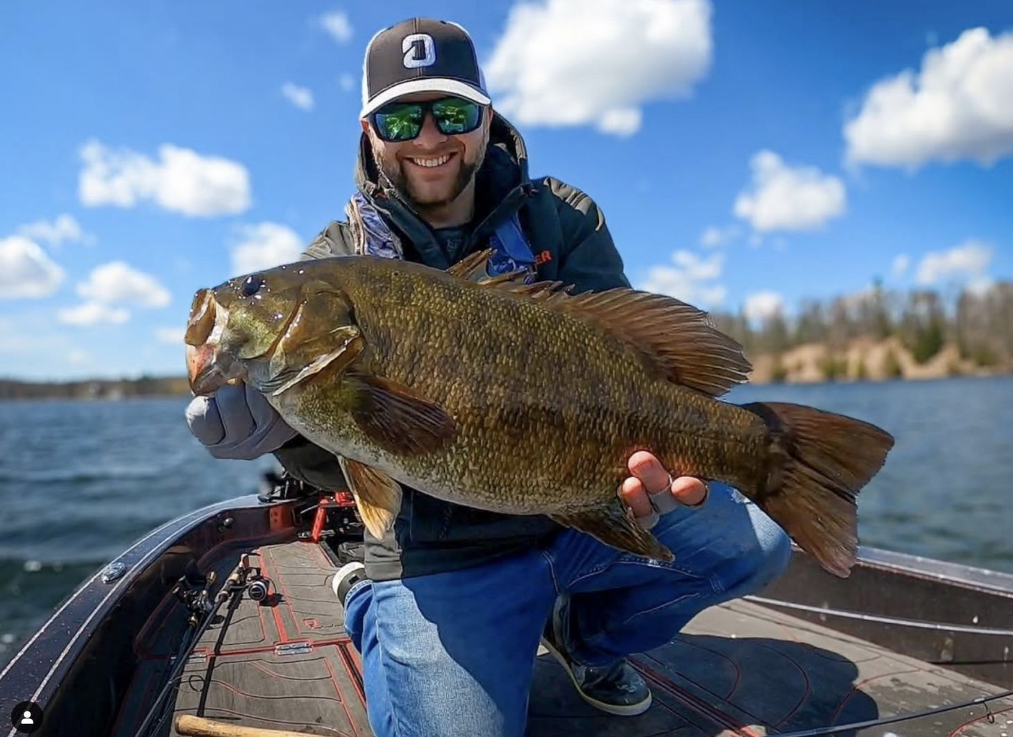 Angler holding up big smallmouth bass on boat