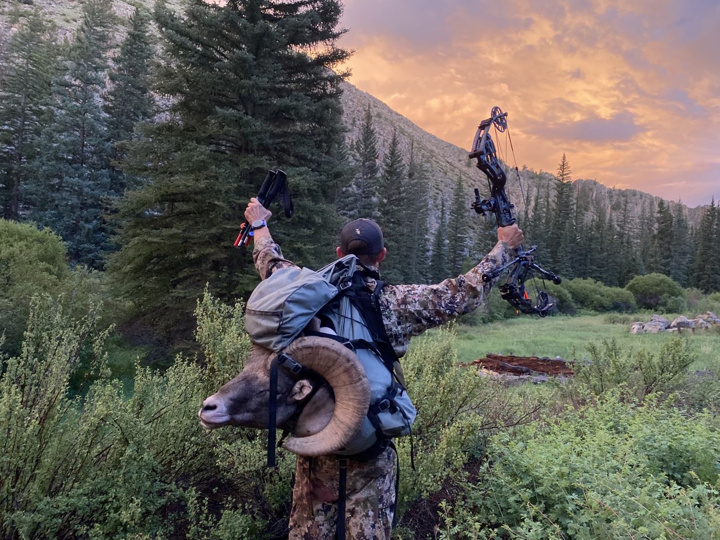 Hunter with hands in the air packing out big horn sheep