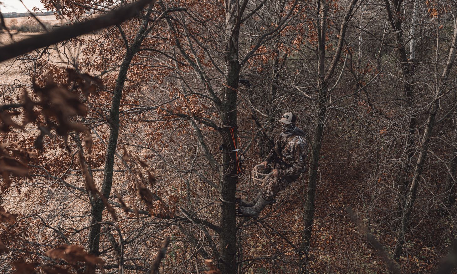 A hunter in a tree stand calls with rattling anlters.