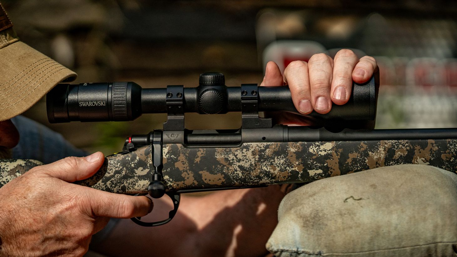 A bench-rest shooter holds the front end of the scope down to keep the muzzle from jumping. 